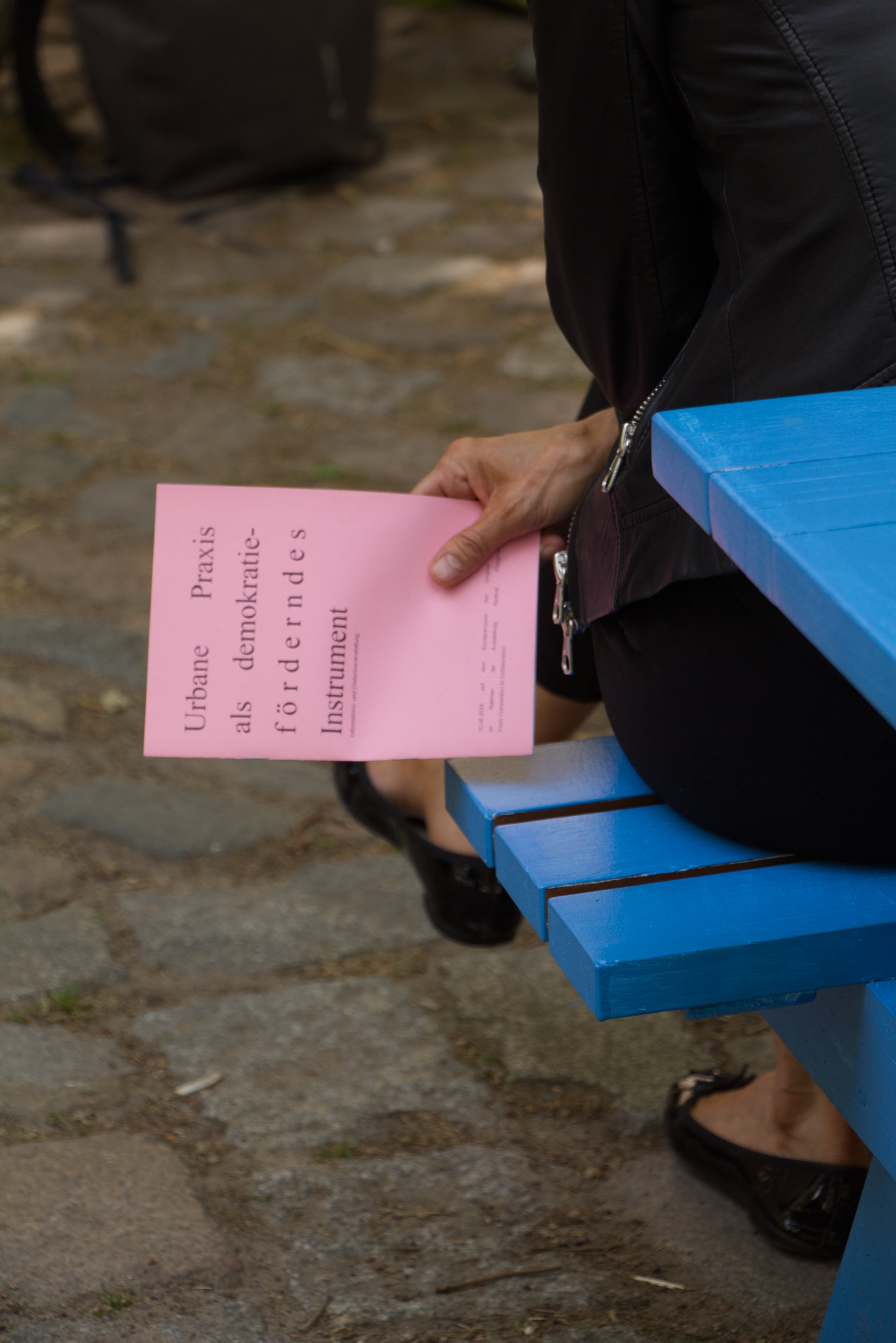 Hand mit Informationsflyer im Gespräch auf dem Gelände des Radical Playgrounds am Gropius Bau.