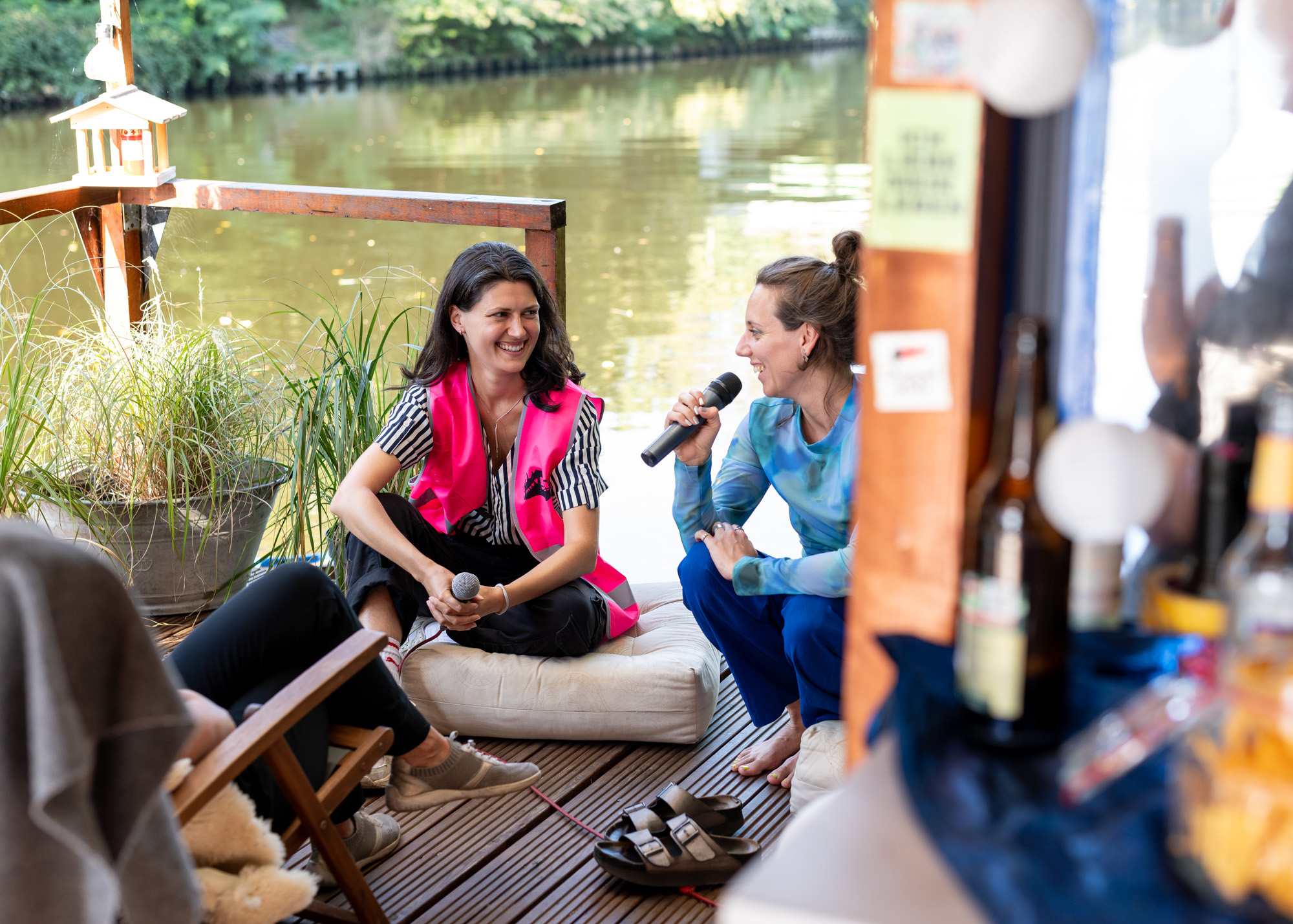 Foto von der Aufnahme bei der Floßtour. Zwei Personen führen ein Gespräch auf dem Floß.
