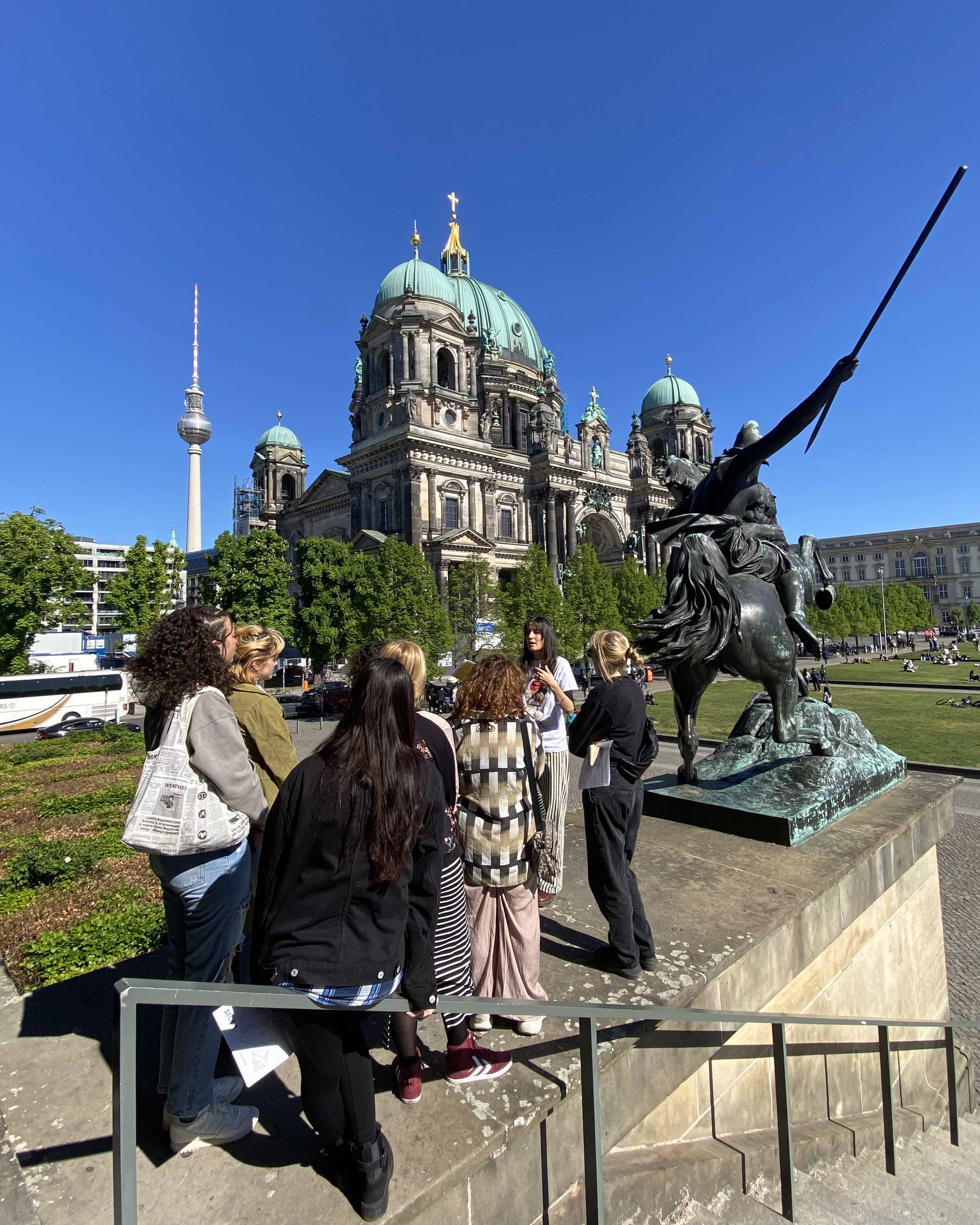 Pesonen schauen sich eine Statue an. Es ist teil einer Stadtführung von Amazonen in Berlin.
